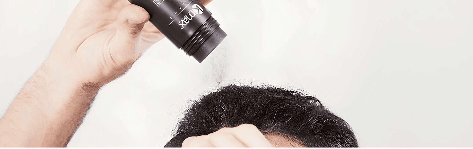 Mano aplicando fibras capilares Kmax sobre el cabello